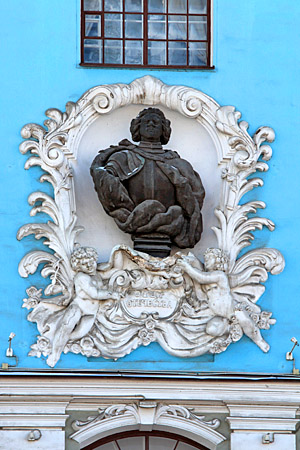Бронзовый бюст облаченного в кирасу и горностаевую мантию Петра I на фасаде Училищного дома имени Петра Великого.